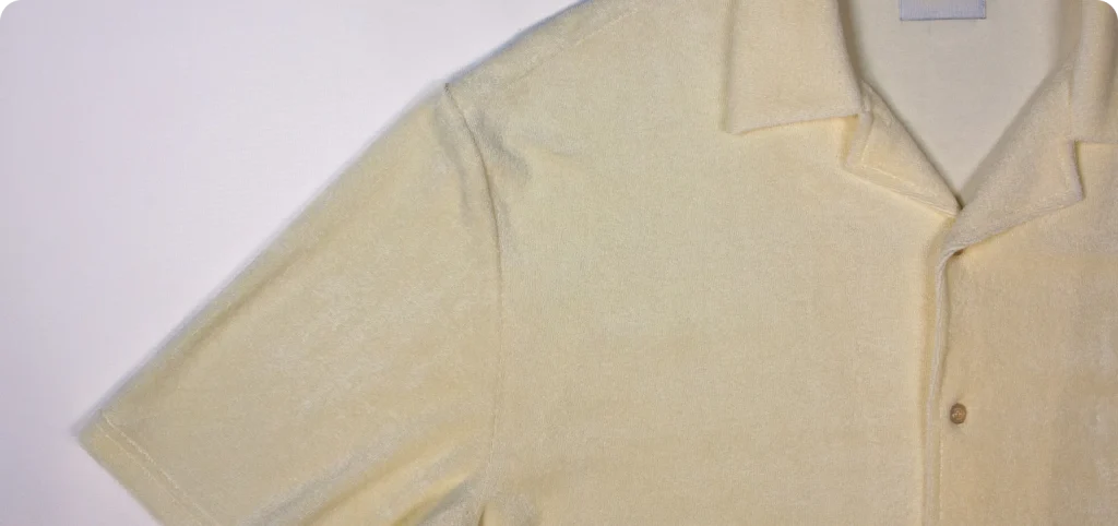 Detalhes da manga e gola do polo bege com botões.