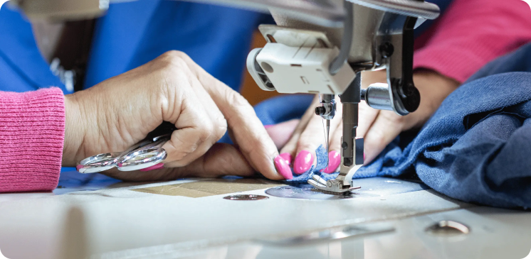 Detalhe de pessoa a costurar, representando o serviço de confeção da Rotex.